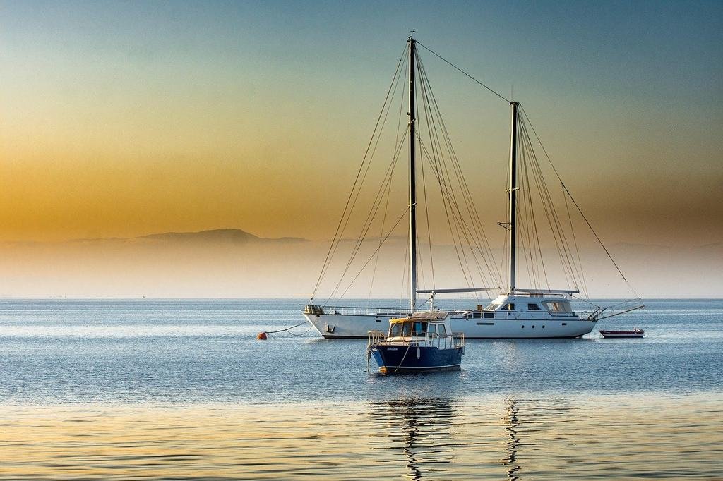 Two sailing boats moored on a calm sea under a golden sunset sky